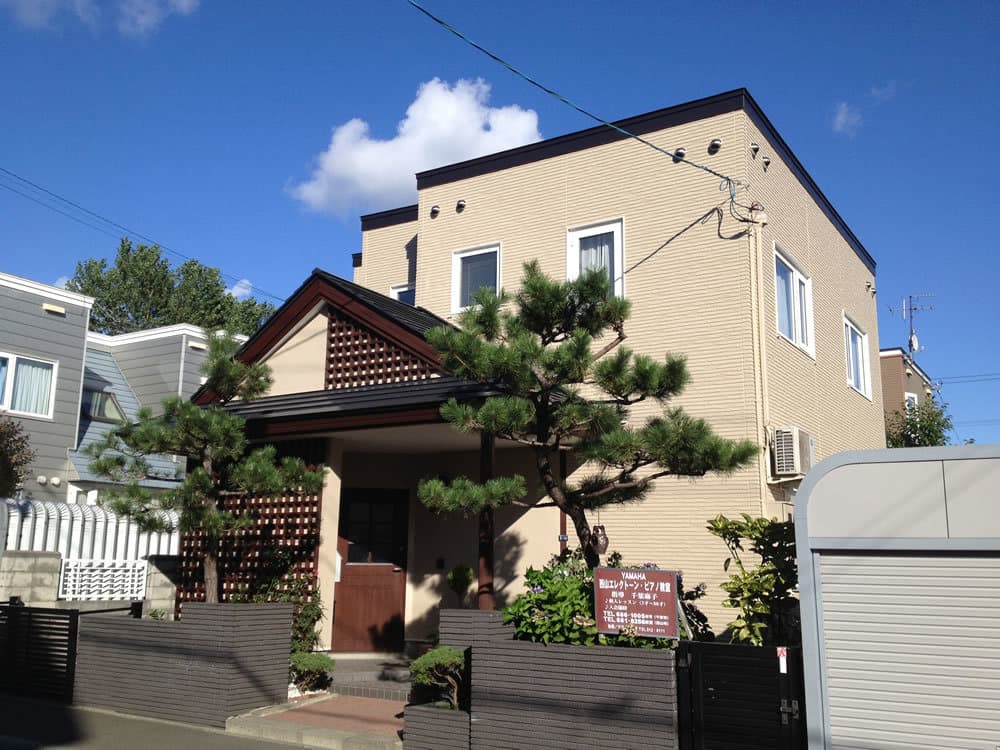 全体のベージュに濃茶のアクセントカラーが映えるサイディング工事を施した戸建て住宅の外観