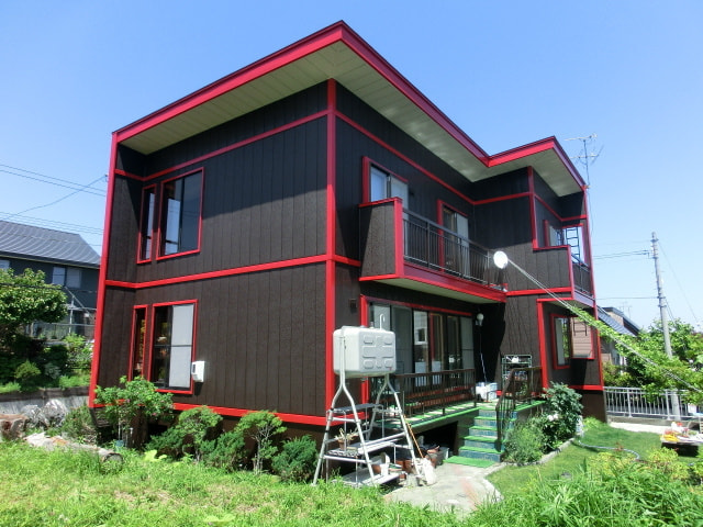 黒い外壁に赤い縁取りが目を引く戸建て住宅の外観